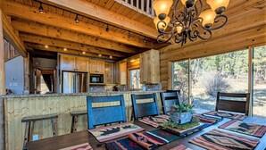 A rustic wooden interior with a dining area featuring a long table with colorful woven placemats and a central plant. - Spectacular Views, Hot Tub, Close to Wolf Creek & San Juan River (Pagosa Springs)
