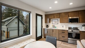 A modern kitchen with wooden cabinets, a built-in oven, and a large window overlooking a residential area.