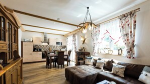 Eine moderne Küche mit Holzausstattung, ein Essbereich mit Tisch und Stühlen sowie ein gemütliches Wohnzimmer mit Ledersofa.
