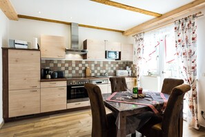 A kitchen with wooden cabinets, a microwave, a stove, and a dining table with chairs.