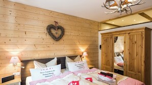 Ein Schlafzimmer mit Holzwand, einer herzförmigen Dekoration, einem Bett mit rot-weißer Bettwäsche und einem Spiegelkorpus.