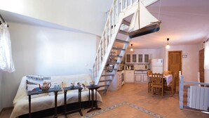 Un vaste espace de vie comprenant un canapé, une table basse et un escalier menant à la cuisine.