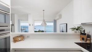 Uma cozinha moderna com vista para o mar, um lustre e uma planta no balcão.
