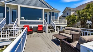 A deck with outdoor furniture, a covered area, and a house with a large window.