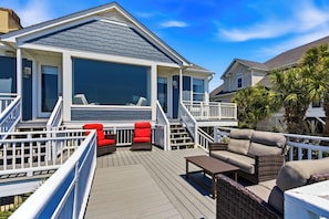 A deck with outdoor furniture, a covered area, and a house with a large window.