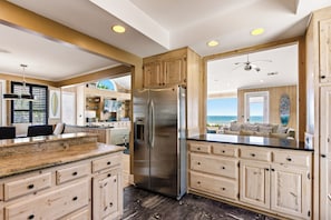 A kitchen with wooden cabinets, a stainless steel refrigerator, and a view of the ocean.