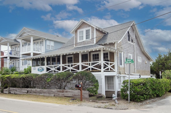 A two-story house with a porch, a mailbox, and a street sign.