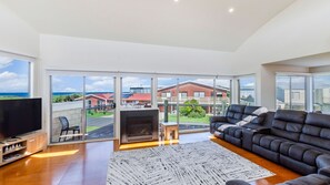 Relax in this stylish living room with a large flat-screen TV, comfortable sofa, and fireplace, offering a view of the ocean.