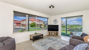 Relax in this stylish living room with a large window offering a view, a flat-screen TV, and a cozy seating area.