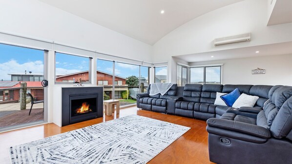 Relax in a spacious living room with a large sofa, fireplace, and expansive views.