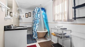 Une salle de bain avec une baignoire, un lavabo, un miroir et un porte-serviettes.