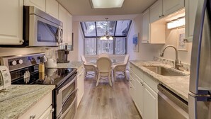 Een moderne keuken met een centraal eiland, roestvrijstalen apparatuur en een groot raam voor natuurlijk licht.