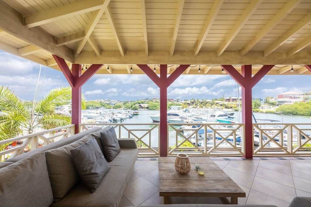 A covered outdoor seating area with a view of a marina.