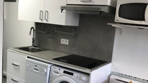 Eine kompakte Küche mit eingebauter Waschmaschine und Trockner, einer Mikrowelle und einer kleinen Essecke.