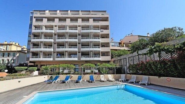 Ein mehrstöckiges Gebäude mit einem Pool und Liegestühlen auf dem Dach.