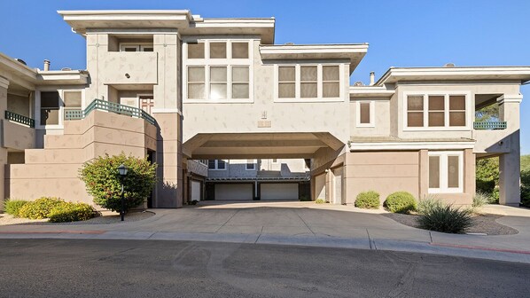 A multi-story residential building with a garage entrance, a covered driveway, and a landscaped front yard. - Kierland/Scottsdale 2BR  Gated, Pool, Spa, 2 car Garage, Universal EV charger (Phoenix)