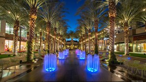 A nighttime view of a shopping area with palm trees, illuminated fountains, and modern buildings. - Kierland/Scottsdale 2BR  Gated, Pool, Spa, 2 car Garage, Universal EV charger (Phoenix)