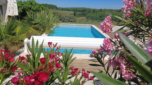A swimming pool surrounded by greenery and flowers. - Gîte Rêve de Caryan (Cuzance)