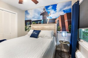 A bedroom with a bed, a pillow with 'Relax' text, a wall-mounted lamp, and a window with curtains.