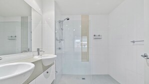 Ein modernes Badezimmer mit einer Duschkabine aus Glas, einem großen Spiegel und zwei Waschbecken.