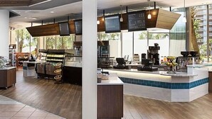 Un café moderne avec un comptoir en bois, un espace salon et de grandes fenêtres.