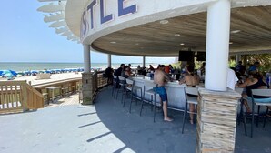 Un espace bar extérieur avec vue sur la plage, une terrasse en bois et une enseigne indiquant « STELLE ».