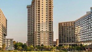 Un grand hôtel à plusieurs étages, une plage au premier plan et des palmiers.