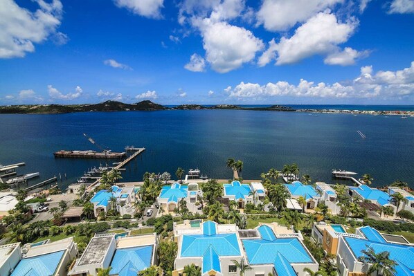 A coastal resort with multiple blue-roofed buildings, a marina with boats, and a clear view of the ocean.