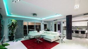 Una sala de estar moderna con un sofá seccional blanco, un tapete rojo y una mesa de centro de vidrio.