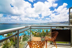 A balcony with a view of a coastal area, including a body of water and a distant mountain range.