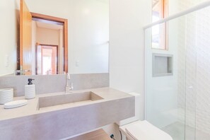 Une salle de bain moderne avec un grand lavabo, un miroir et une douche.