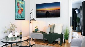 A modern living room with a sofa, a coffee table, and a TV mounted on the wall. - Prospect Cottage Ballarat (Golden Point)