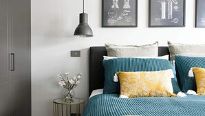 A modern bedroom with a bed, a side table, and a wall-mounted pendant light. - Prospect Cottage Ballarat (Golden Point)