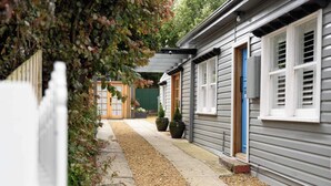 A row of single-story houses with a gravel pathway, wooden fences, and potted plants. - Prospect Cottage Ballarat (Golden Point)
