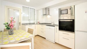 Una cocina moderna con armarios blancos, microondas, horno y cafetera.