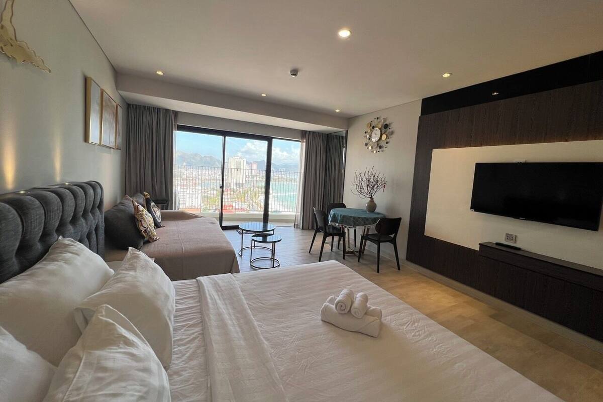 Een hotelkamer met twee bedden, een televisie, een bureau en uitzicht op de stad.