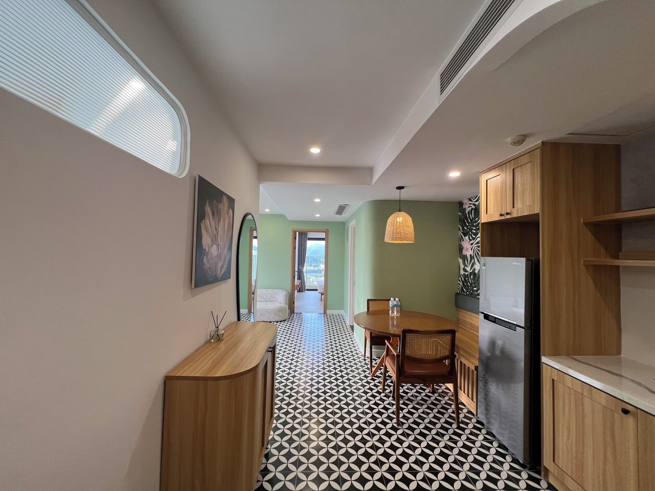 A modern kitchen with a black and white patterned floor, wooden cabinets, and a dining area with a table and chairs.