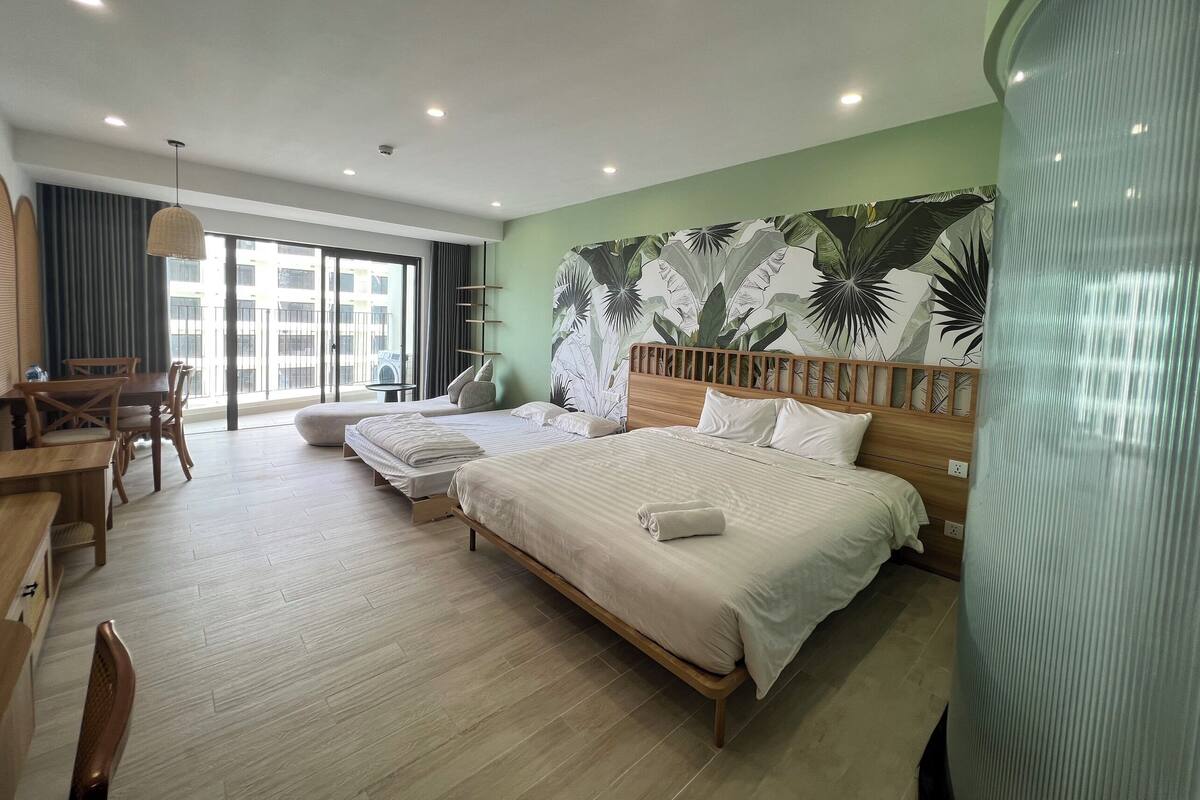 Een hotelkamer met twee bedden, een zithoek en een groot raam met uitzicht op gebouwen.