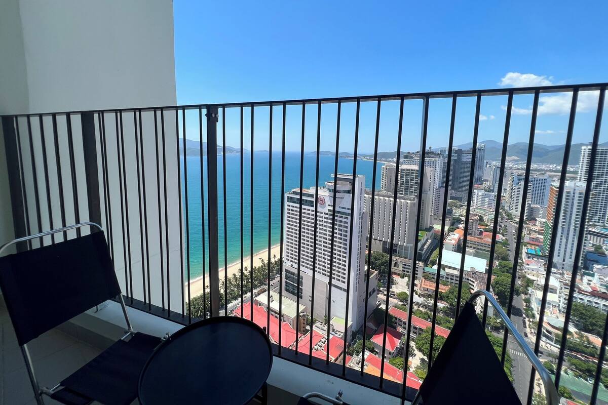 Een balkon met uitzicht op een strand en stadsbeeld.
