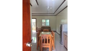 Un comedor con mesa y sillas de madera, un refrigerador y una ventana con persianas.