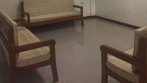 Una habitación con un sofá, dos sillones, una cortina y una lámpara.