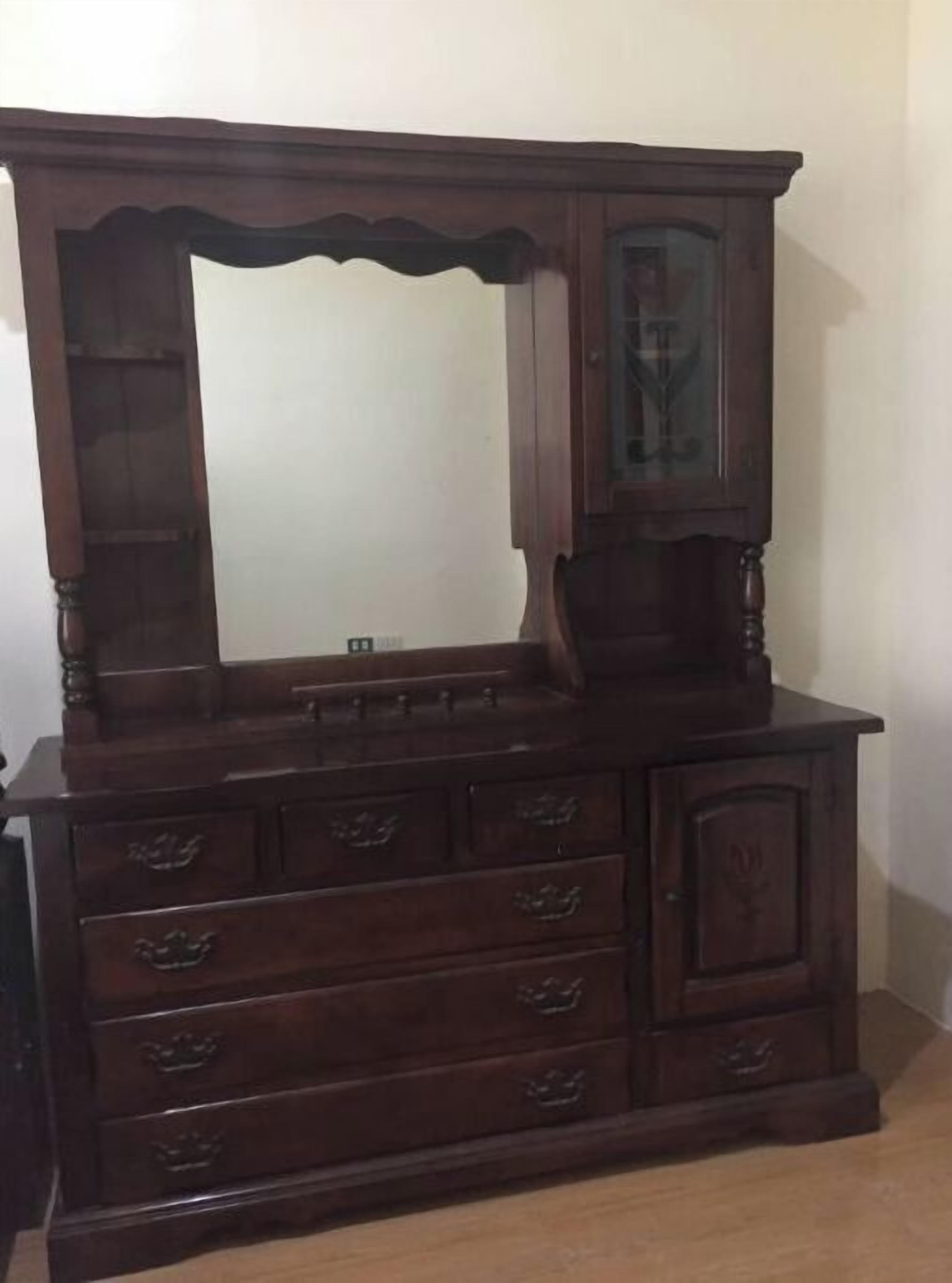 A wooden dresser with a large mirror and multiple drawers.