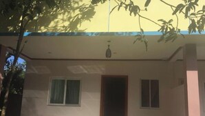 Un edificio de dos plantas con techo plano, una entrada central y dos ventanas en la planta baja.