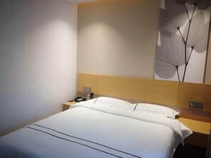 Ein Hotelzimmer mit einem Bett, einem Nachttisch mit Telefon und einer Wandleuchte.