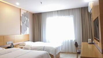 Habitación de hotel con dos camas, un escritorio, una silla y un ventanal con cortinas.