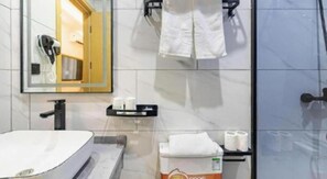 Un baño moderno con cabina de ducha de vidrio, un lavamanos blanco y un espejo con marco de madera.