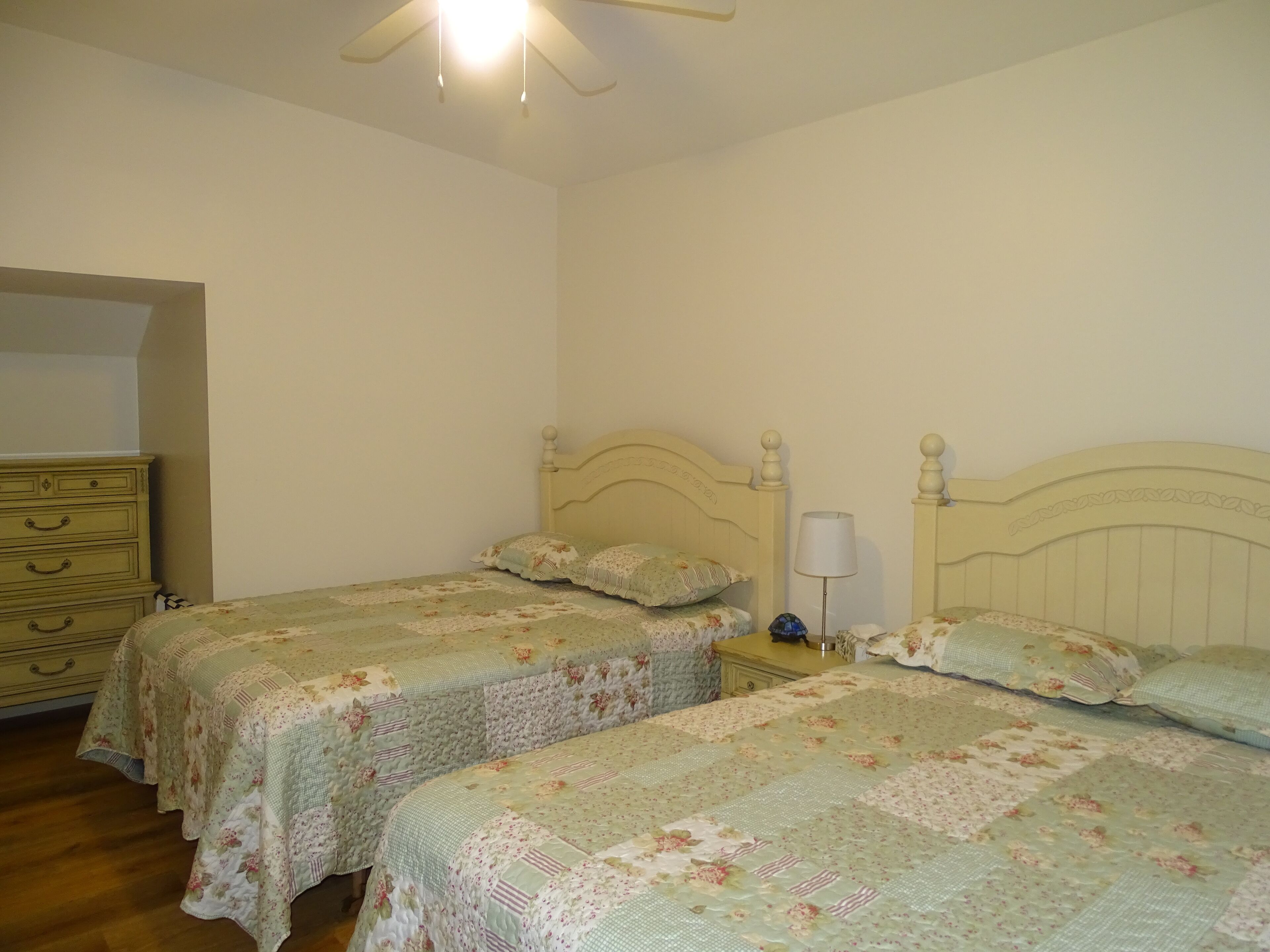 Un dormitorio con dos camas individuales, un aparador y una mesita de noche con lámpara.