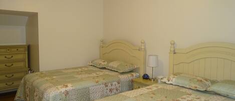 A bedroom with two single beds, a dresser, and a nightstand with a lamp.