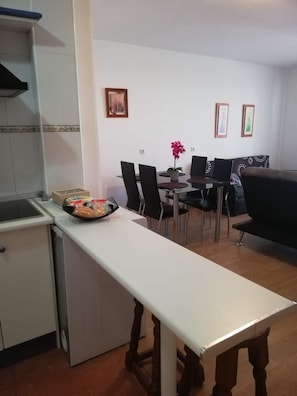 A compact kitchen with a dining area, a small refrigerator, and a dining table with chairs.