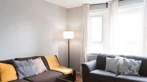 A modern living room with two sofas, a floor lamp, and a large window with curtains.
